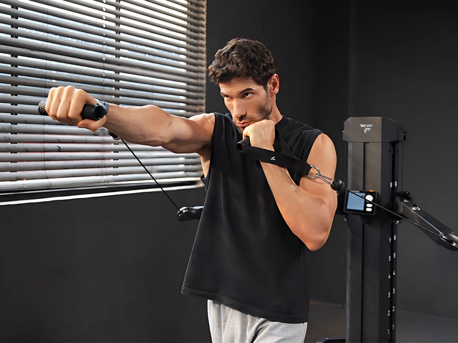 A man performs a cable punch exercise on a fitness machine, focusing intensely as he extends his arm forward
