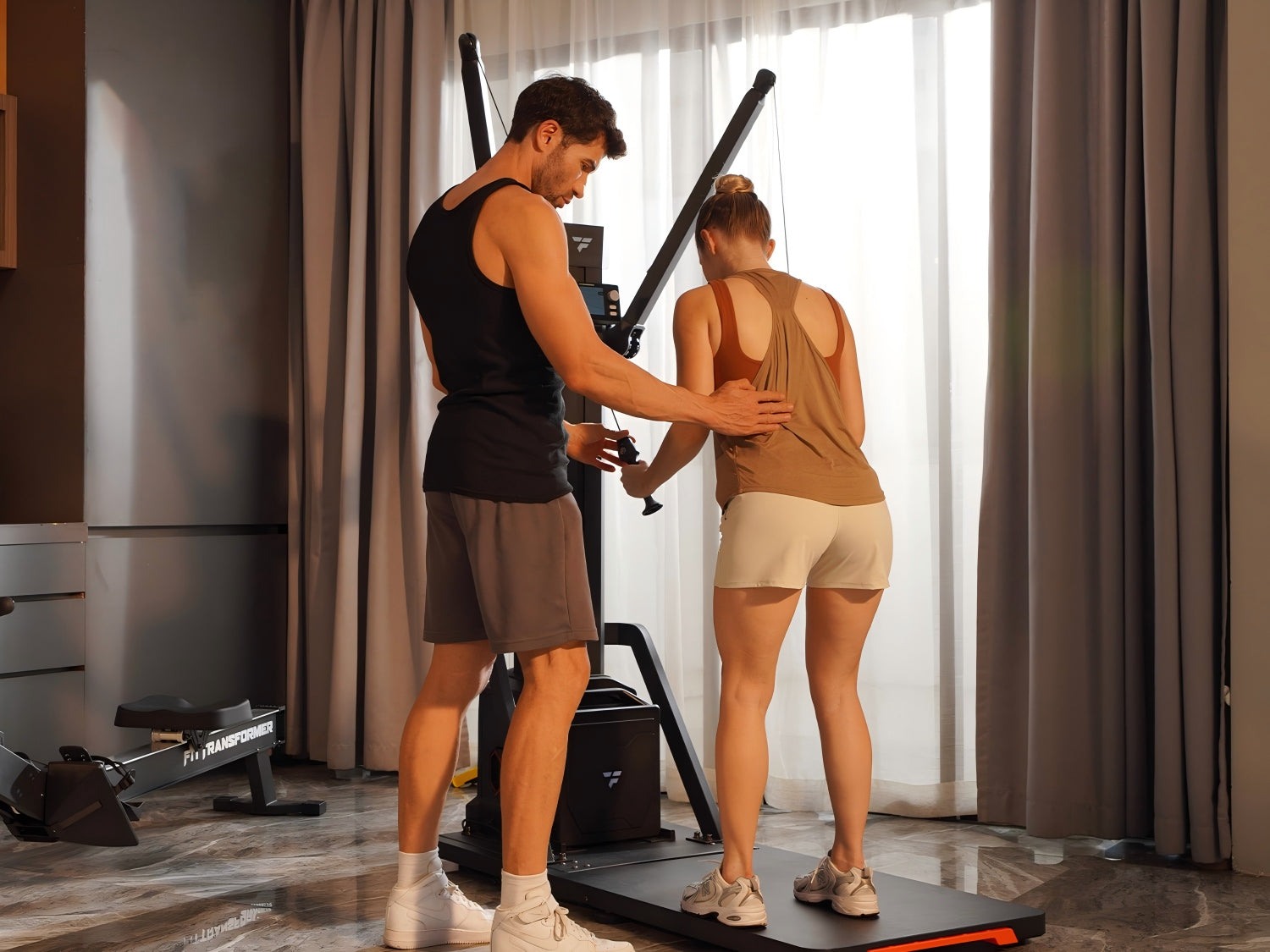 A man guiding a woman using a smart home cable gym machine in a sunlit living room